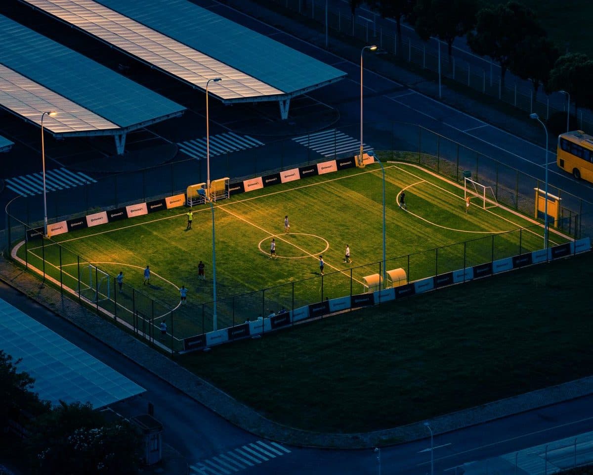 Cancha de fútbol 5 iluminada de noche con jugadores en un complejo deportivo