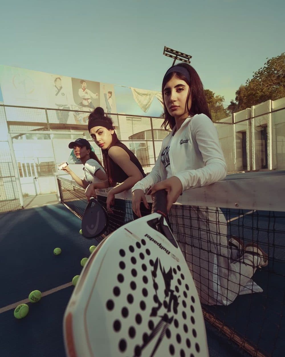 Jugadoras de pádel con sus paletas en la red de una cancha al aire libre